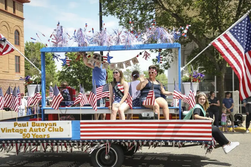 Parade float with American flags and people in red white and blue.