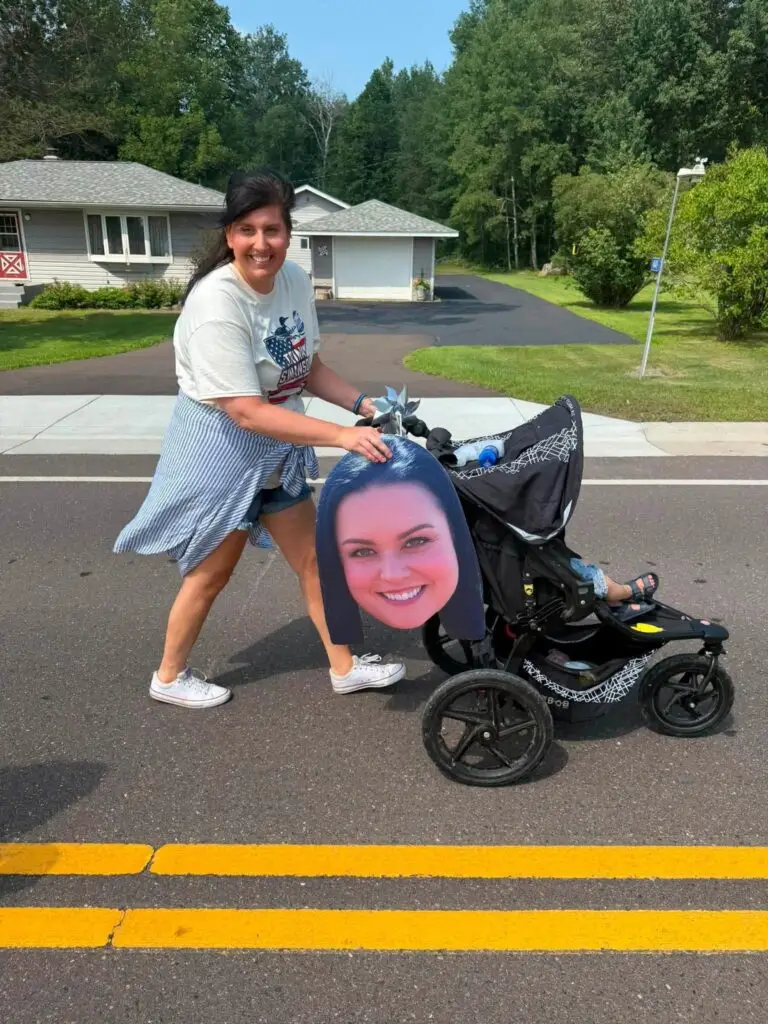 Woman with a stroller and giant head cutout of Trina's face.